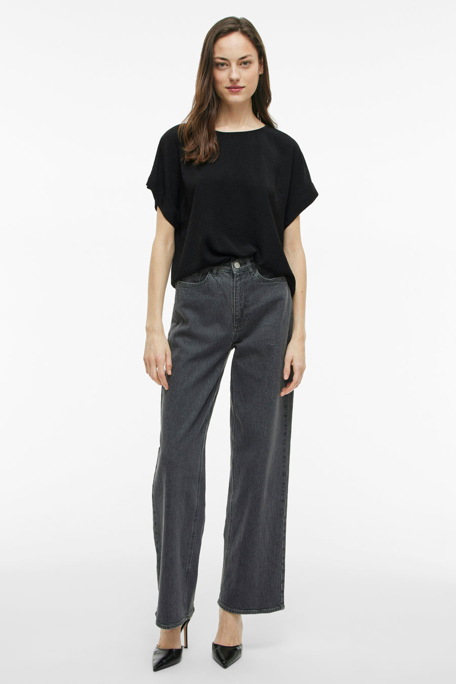Zwart T-shirt met korte mouwen van VILA, gedragen met een lichtgrijze jeans en zwarte pumps.