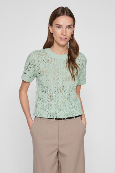 Groene trui met ronde hals in opengebreide stof van VILA, gedragen met een beige broek met hoge taille.
