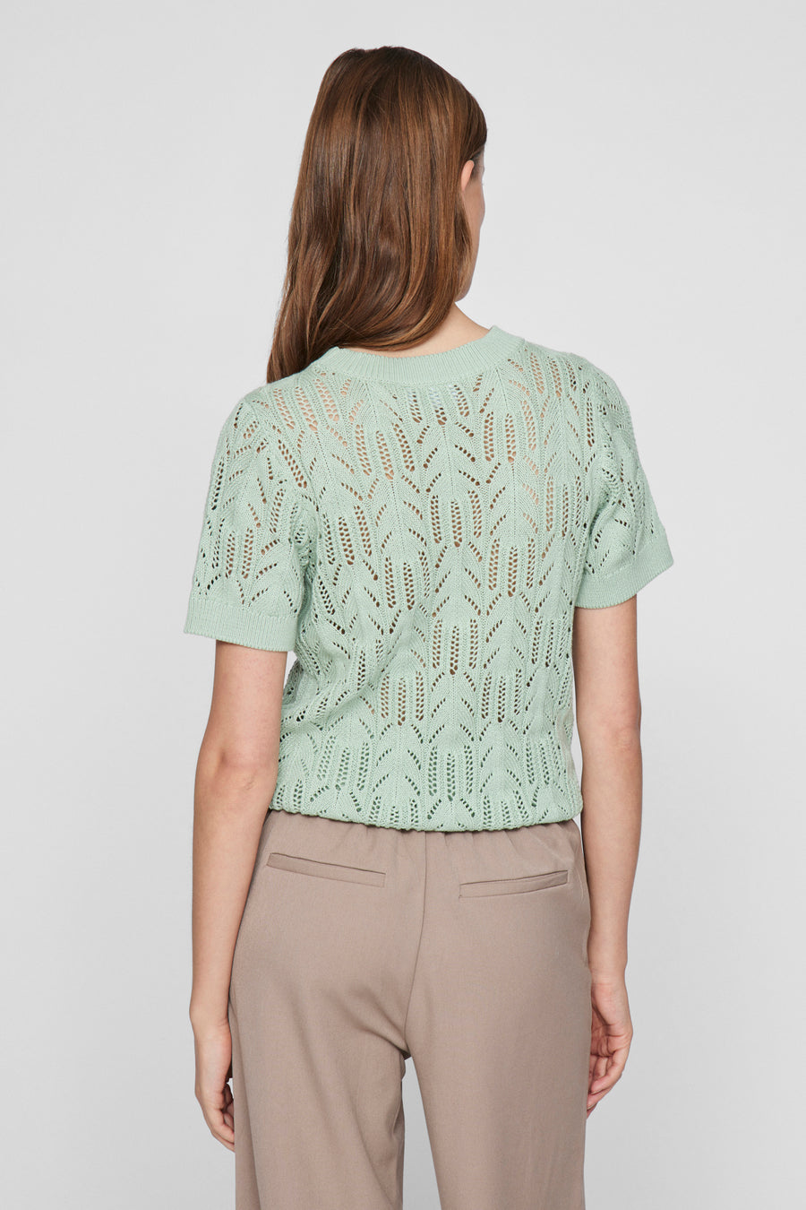 Groene trui met ronde hals van VILA®, met ajourpatroon en korte mouwen, gedragen met een beige broek.