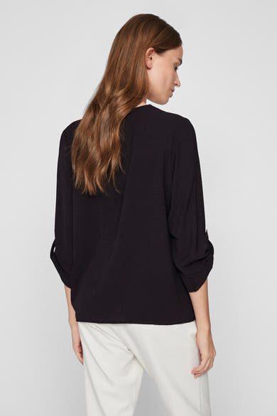 Zwarte blouse met lange mouwen van VILA, met opgerolde zomen, gedragen met een witte broek.
