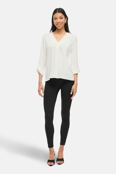 Blouse à manches longues blanche de VILA, avec des manches retroussées et un décolleté en V.
