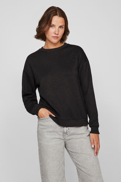 Zwarte rondehals sweatshirt van VILA, gedragen met een lichtgrijze broek, één hand in de zak.