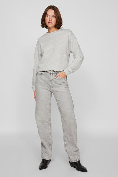 Sweat-shirt gris par Vila, porté avec un jean taille haute délavé et des bottines en cuir noires.