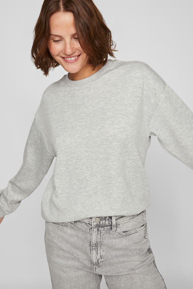Grijze sweater van VILA®, gedragen met een verbleekte spijkerbroek en een relaxte pasvorm.