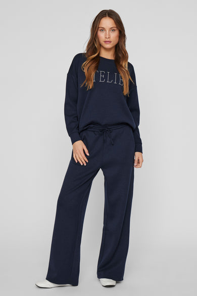 Pantalon coloré bleu de VILA, large et confortable, porté avec un pull assorti.