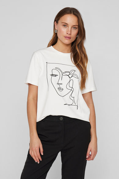 T-shirt blanc à manches courtes de VILA®, orné d'un dessin minimaliste en noir, porté avec un pantalon noir.

