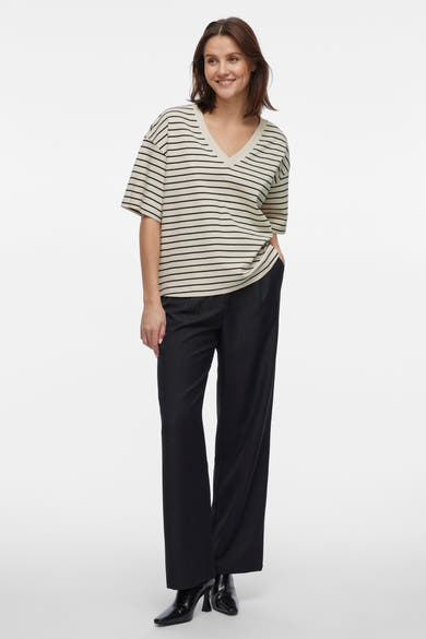 Beige T-shirt met korte mouwen van VILA®, met zwarte strepen, gedragen met een wijde zwarte broek en enkellaarsjes.
