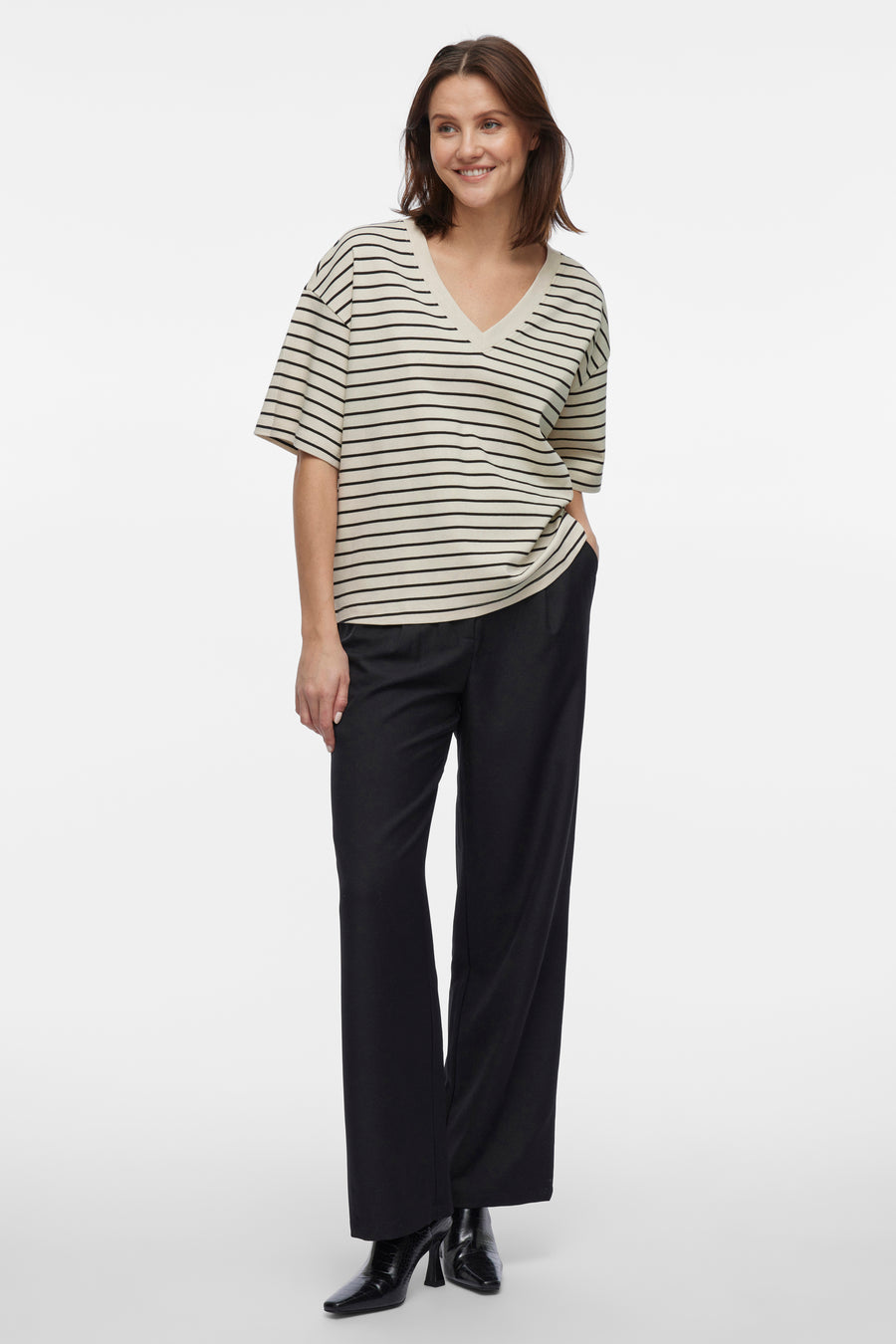 Beige T-shirt met korte mouwen van VILA®, met zwarte strepen, gedragen met een wijde zwarte broek en enkellaarsjes.