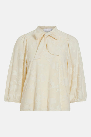 Blouse à manches longues écru de VILA, avec un nœud au col et un motif floral ton sur ton.
