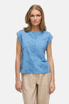 Top bleu sans manches VILA® avec broderies florales, porté avec un pantalon beige.
