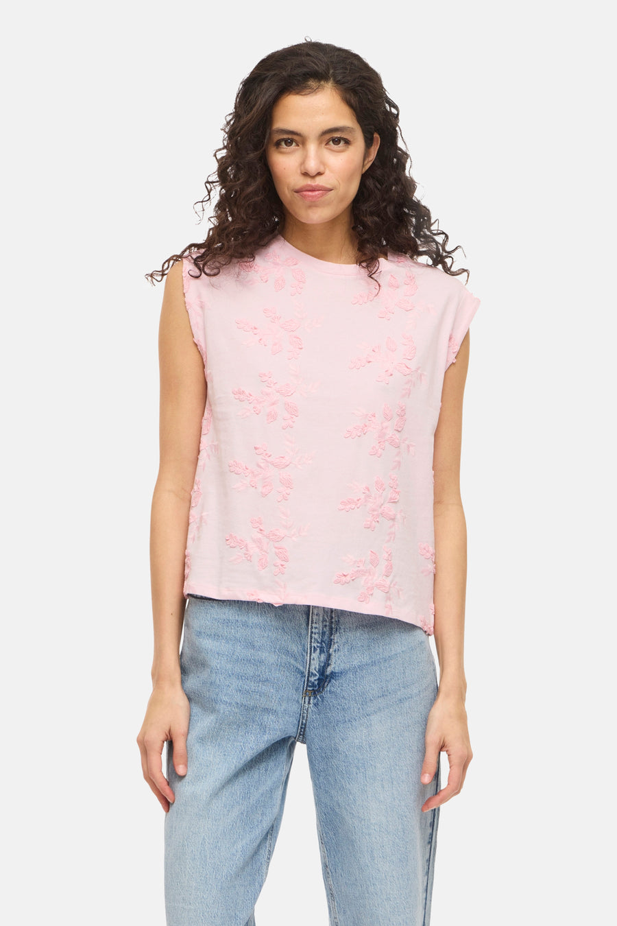 Roze mouwloze top van VILA® met toon-op-toon bloemenborduursel; gedragen met een lichtblauwe jeans en zwarte muiltjes.