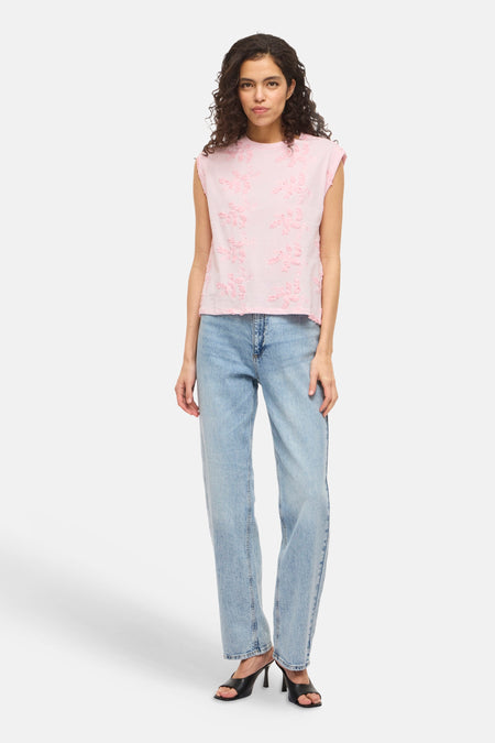 Top sans manches rose de VILA®, avec broderie florale ton sur ton ; porté avec un jean bleu clair et des mules noires.
