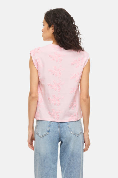 Roze mouwloze top van VILA®, versierd met delicate bloemenborduursels, gedragen met een wijde spijkerbroek.