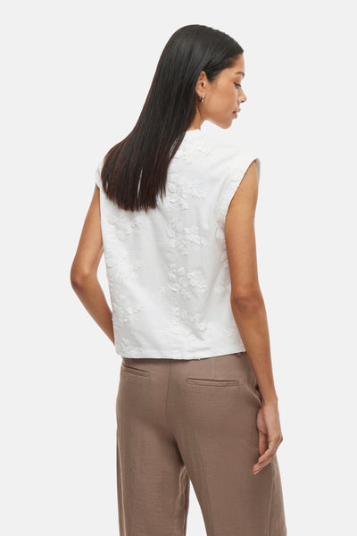 Top sans manches blanc de VILA®, avec motif floral en relief, porté avec un pantalon marron.