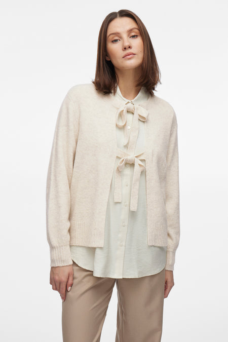 Beige gilet van VILA®, gedragen over een blouse met strik en een zandkleurige broek.