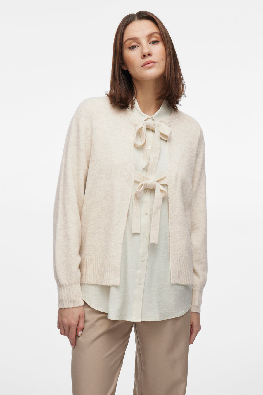 Beige gilet van VILA®, gedragen over een blouse met strik en een zandkleurige broek.