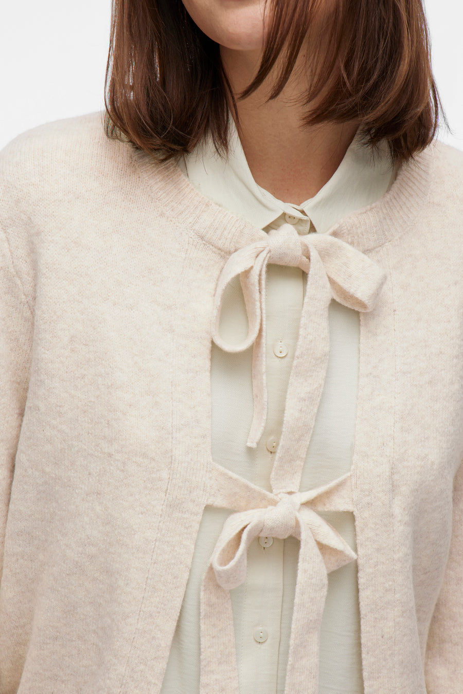 Beige gilet van VILA, met strikbandjes over een lichtgekleurd overhemd met knopen.