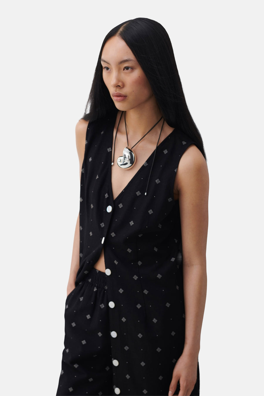Zwarte jurk met geometrische patronen van VILA, met witte knopen en een zilveren ketting.