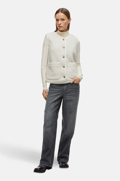 Gilet écru de VILA, porté sur un pull à col roulé crème et un jean gris anthracite.
