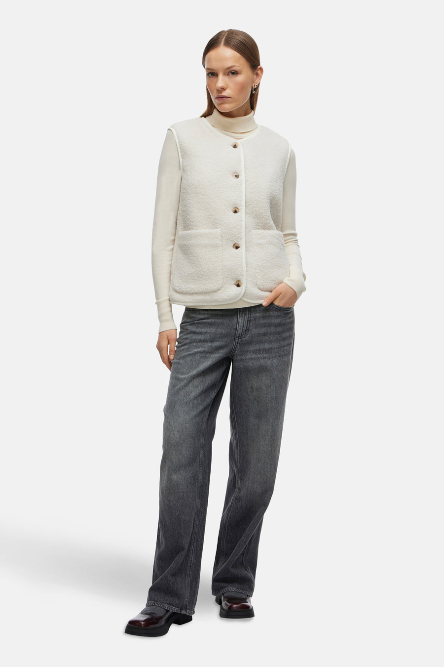Gilet écru de VILA, porté sur un pull à col roulé crème et un jean gris anthracite.