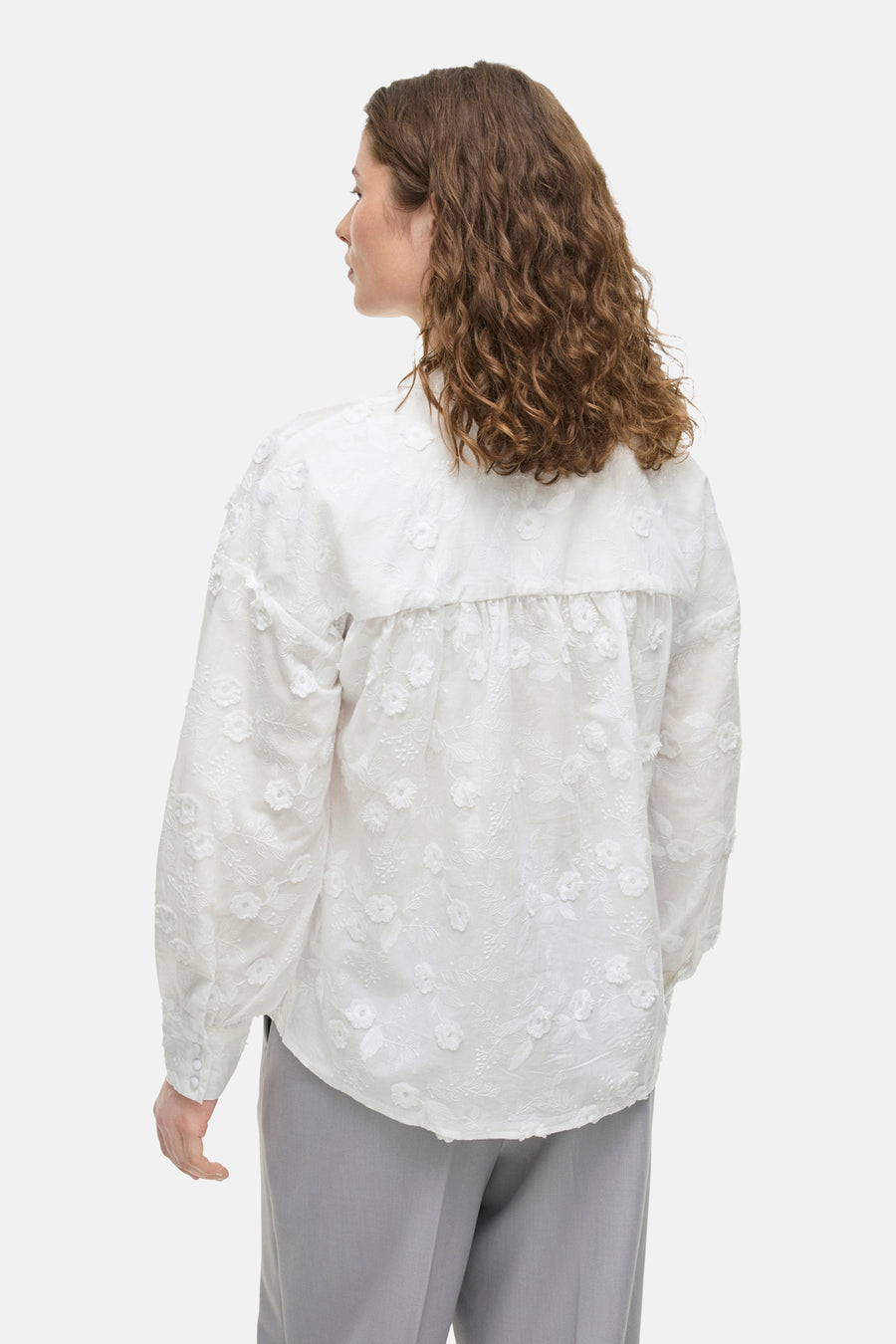 Wit overhemd met lange mouwen van VILA, versierd met bloemenborduursels, gedragen met een grijze broek.