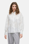 Wit overhemd met lange mouwen van VILA, met delicate bloemenborduursels, gedragen met een grijze broek.