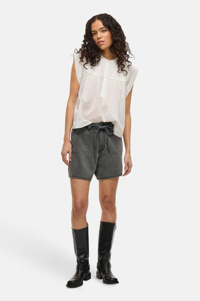 Short gris de VILA, porté avec une blouse blanche et des bottes noires hautes.