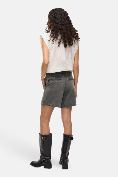 Short gris de VILA, porté avec un chemisier blanc et des bottes noires hautes.
