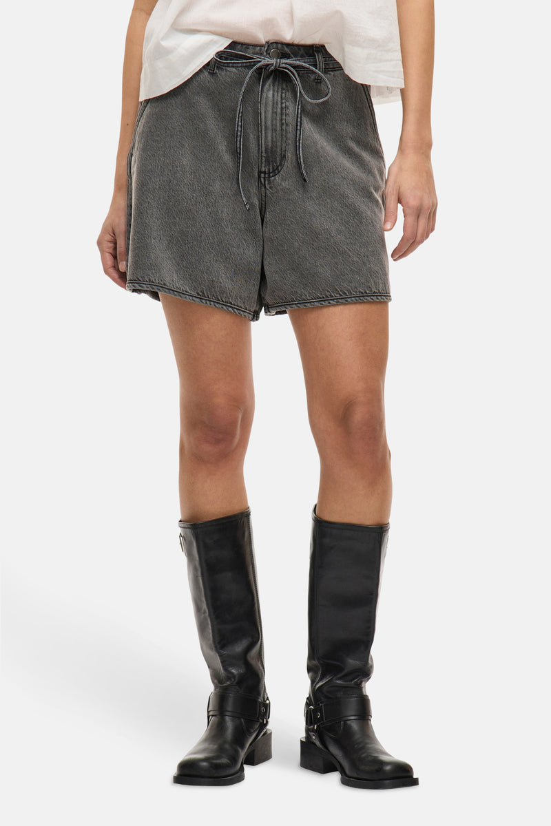 Short gris de VILA, porté avec des bottes hautes en cuir noir et un t-shirt blanc.