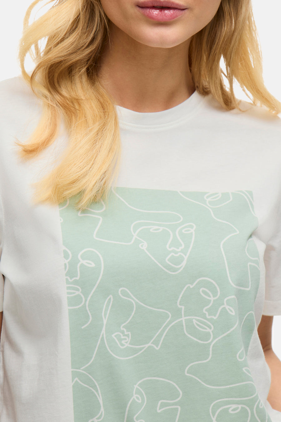 T-shirt blanc à manches courtes de Vila, avec motif de visages abstraits vert d'eau.
