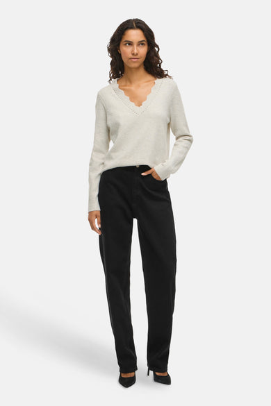 Beige V-hals trui van VILA® met geschulpte details, gedragen met een zwarte high-waist jeans en zwarte pumps.