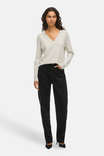 Beige V-hals trui van VILA® met geschulpte details, gedragen met een zwarte high-waist jeans en zwarte pumps.