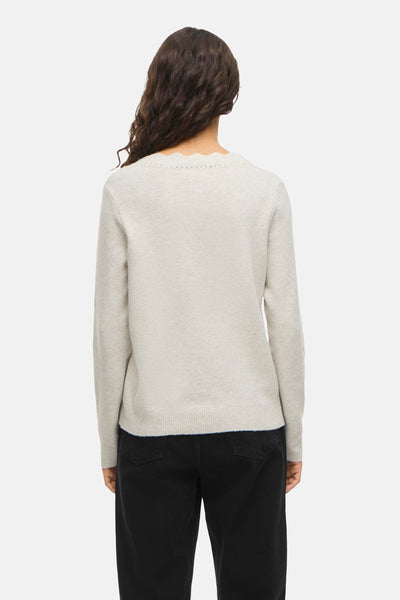Beige V-hals trui van VILA® met ajourdetails, gedragen met een zwarte jeans.