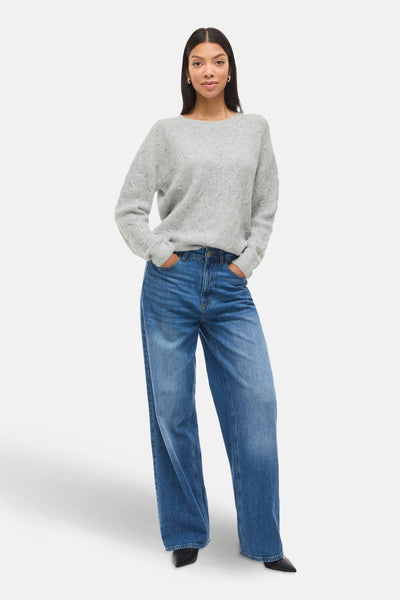 Pull gris à col rond de VILA, avec un motif en maille torsadée, porté avec un jean bleu ample.