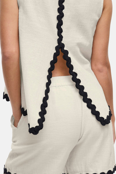 Blouse écru sans manches de VILA®, ornée d'une bordure festonnée noire et d'une ouverture au dos.
