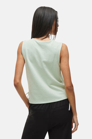 Groen mouwloos topje van VILA® met wafelstructuur en zijdelingse bandjes, gedragen met een zwarte broek.