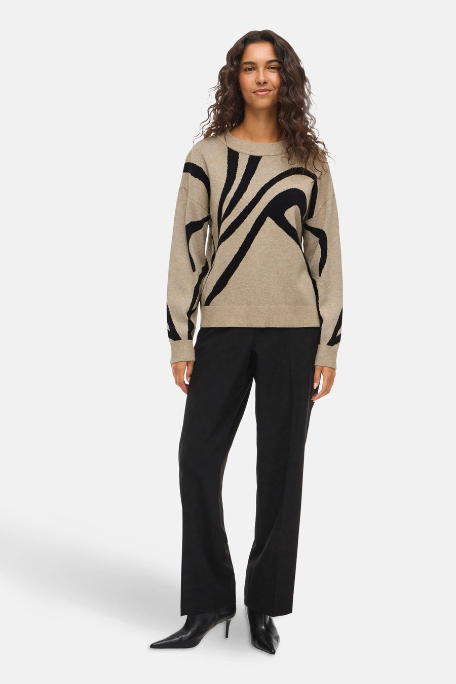 Beige ronde hals trui van VILA, met zwart grafisch patroon en gedragen met een zwarte broek.
