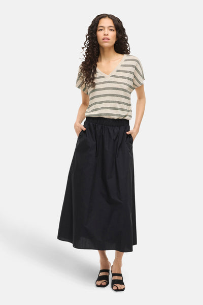 T-shirt kaki à manches courtes de VILA, rayé beige et vert, porté avec une jupe longue noire.
