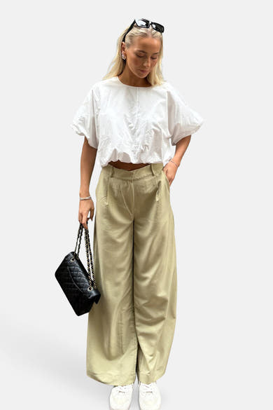 Pantalon vert de VILA®, ample avec des plis et porté avec un haut blanc et un sac noir.