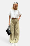 Pantalon vert de VILA®, ample avec des plis et porté avec un haut blanc et un sac noir.