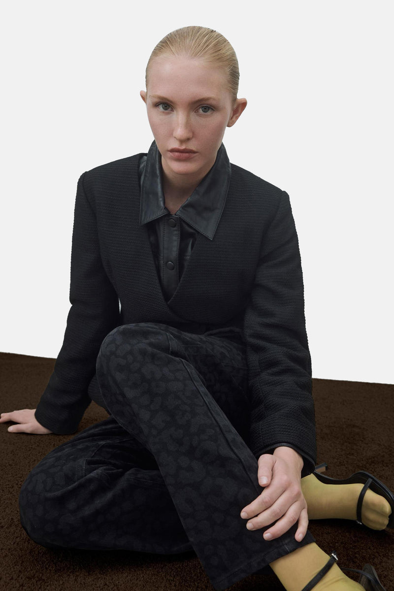 Jean noir de VILA®, avec un motif subtil, porté avec une veste noire et des chaussures à talons.
