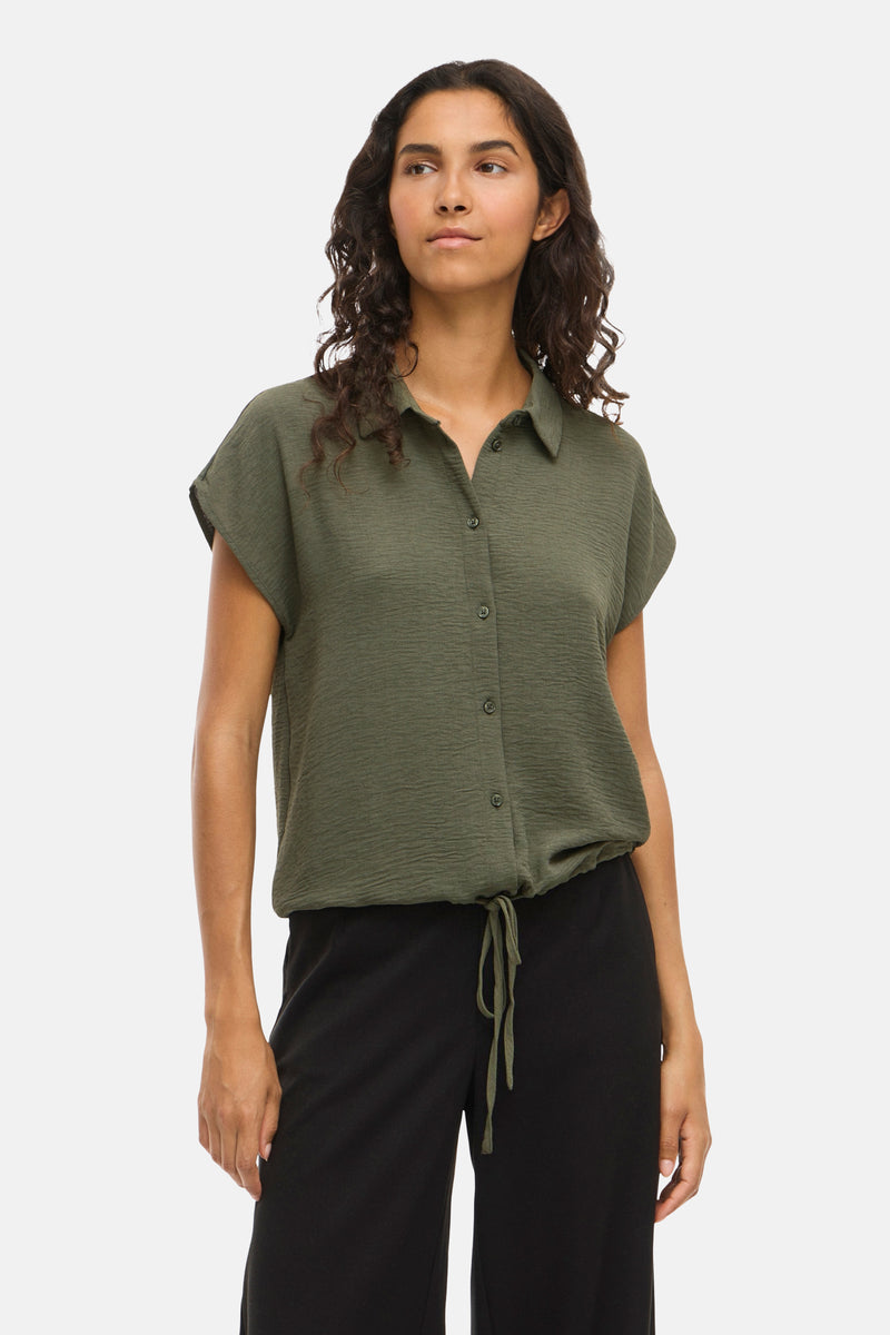 Kaki blouse met korte mouwen van VILA, gedragen met een wijde zwarte broek.
