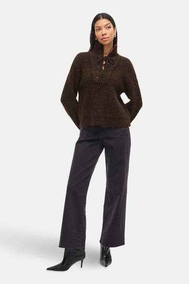 Pull brun en maille de VILA®, avec un col montant lacé et porté avec un jean noir et des bottines pointues.