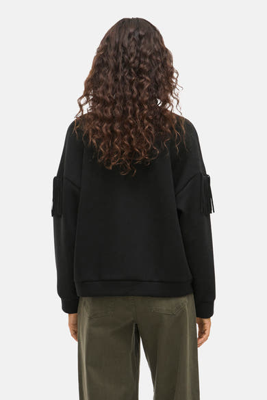 Zwarte trui van VILA, lange mouwen met franjes, gedragen met een olijfgroene broek, achterzicht.