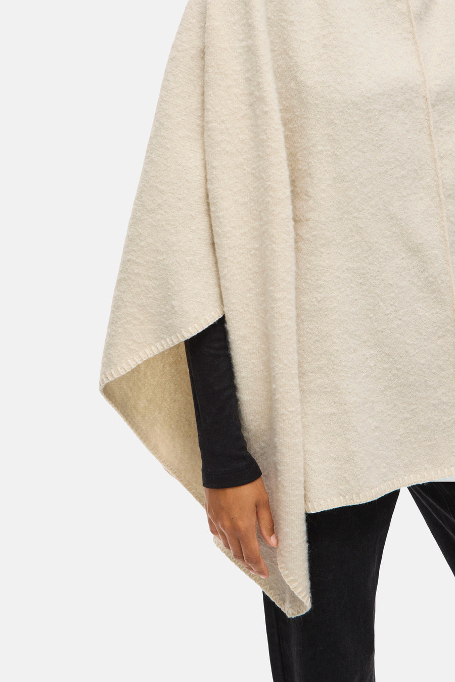 Beige grofgebreid poncho van VILA, gedragen over een zwarte top met lange mouwen.