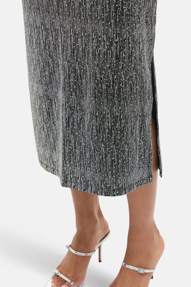 Glitterende lange zilveren rok van VILA®, met een zijsplit, gedragen met zilveren naaldhak sandalen.