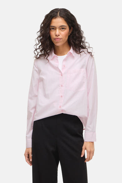 Chemise rose à rayures verticales de VILA, portée ouverte sur un t-shirt blanc et un pantalon noir.