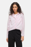 Chemise rose à rayures verticales de VILA, portée ouverte sur un t-shirt blanc et un pantalon noir.