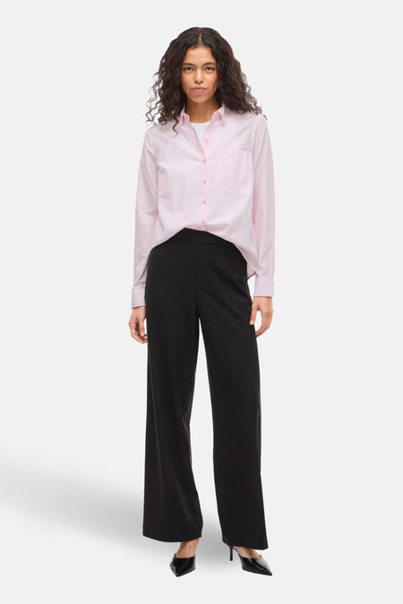 Chemise à manches longues rose VILA®, portée ouverte sur un t-shirt blanc, avec un pantalon noir large et des escarpins noirs vernis.