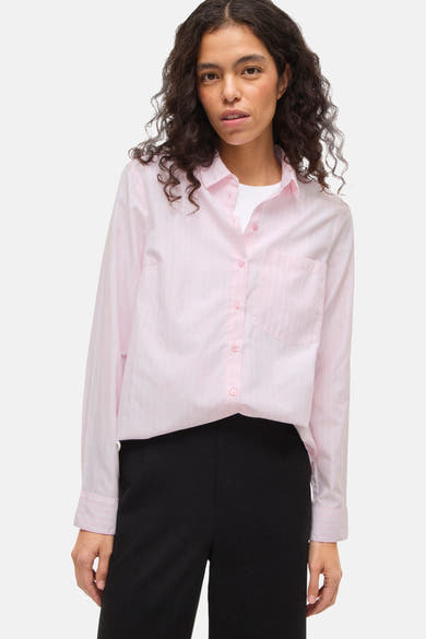 Chemise à manches longues rose rayée de VILA, portée sur un t-shirt blanc et un pantalon noir taille haute.